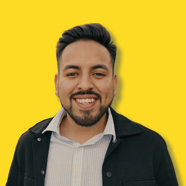 Dave Sotelo in white shirt, black jacket against yellow background